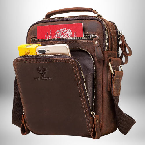 Un sac de ville homme en cuir marron avec de nombreuses poches zippées et une poignée sur le dessus.
