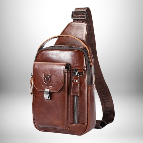 Un sac bandoulière en cuir marron avec une poche avant et une bandoulière. Le sac a une poignée de transport supérieure et une fermeture à glissière. La bandoulière porte le nom « BULL LO ».