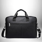 Un sac de style mallette noir est posé sur fond blanc. Le sac a une poignée de transport supérieure et une bandoulière amovible. Il comporte également une poche zippée sur le devant.
 — vue 3