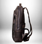 Photographie latérale d'un sac à dos en cuir marron foncé vu en détail, avec une fermeture éclair et des bretelles. — vue 3